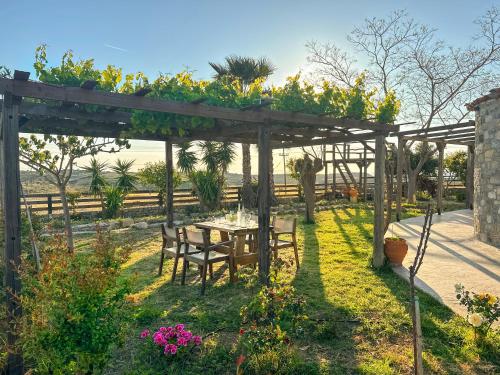 a wooden pergola with a table in a garden at Casa De Linda in Antimácheia