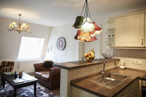 a kitchen with a sink and a living room at Aparthotel Bernstein in Büsum
