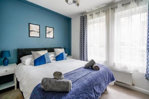 a bedroom with a large bed with blue walls at The Augustine - Modern two Bed Ground floor apartment with parking in Canterbury