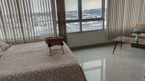 a bedroom with a bed and a table and windows at Suite Ejecutiva en excelente ubicación con Piscina-Parqueo-Gym-Seguridad 24/7 in Guayaquil