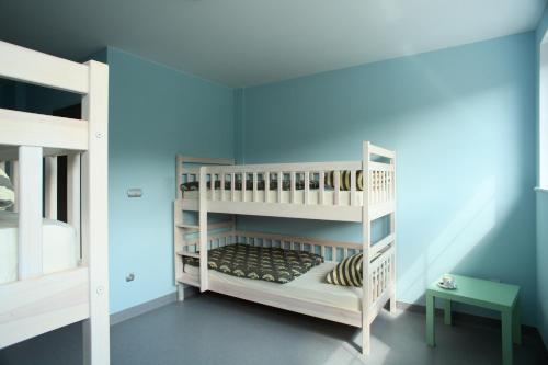 イェドリナ・ズドルイにあるHostel Browar Jedlinkaの白い二段ベッドと青い壁が備わる客室です。