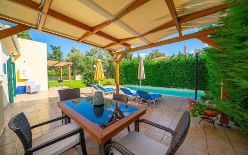 a patio with a table and chairs and an umbrella at Dafni (2 bedrooms, sleeps 4) in Sami