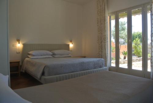 1 dormitorio blanco con 2 camas y ventana en Villa Carlotta Resort, en San Leone