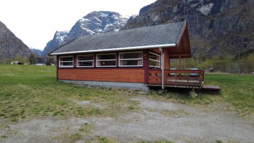 a small cabin in a field with mountains in the background at Sæbø Camping in Eidfjord
