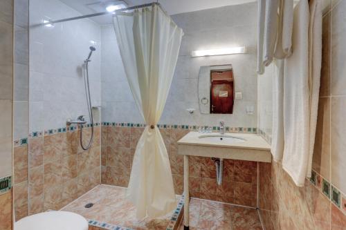 een badkamer met een douche, een wastafel en een toilet bij Ellinis Hotel in Varna