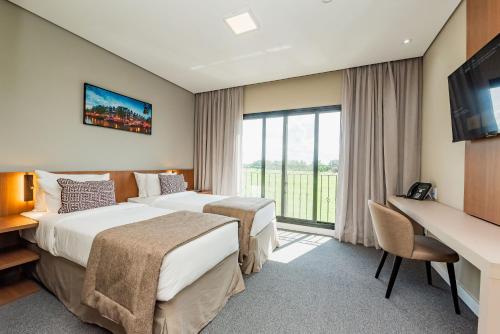 a hotel room with two beds and a desk at Royal Tulip Holambra in Holambra