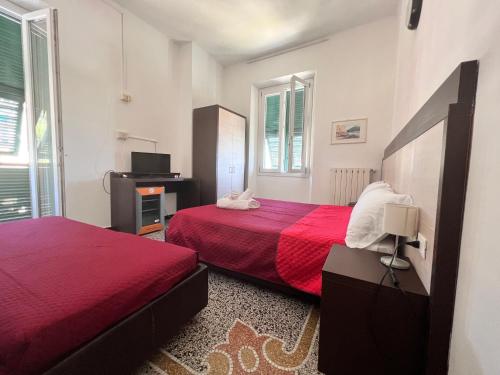 ein Schlafzimmer mit zwei Betten mit roter Bettwäsche und einem Fernseher in der Unterkunft Hotel Monique in Noli
