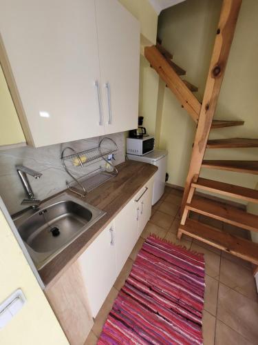 a small kitchen with a sink and a staircase at Adeles sodyba in Sturmai
