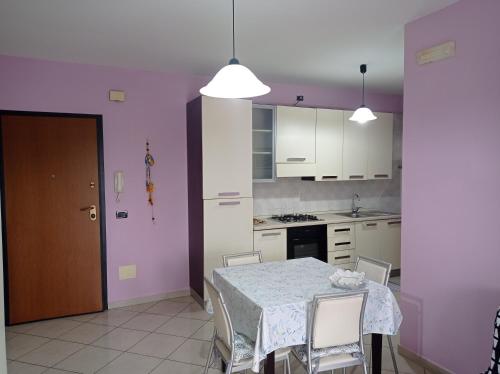 una cocina con mesa y sillas y una cocina con paredes púrpuras. en Appartamento tra mare e città, en Vasto