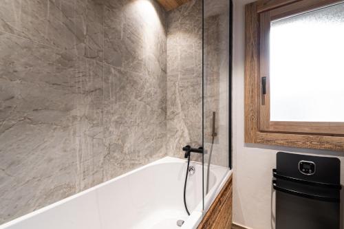 uma casa de banho com uma banheira branca e uma janela em Chalet Isatis em Megève