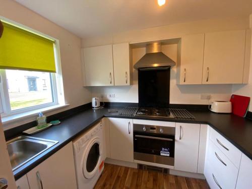 uma cozinha com um lavatório e um fogão forno superior em 3 bed house with parking near airport em Edimburgo