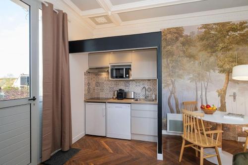 une cuisine avec des armoires blanches et une table dans une pièce dans l'établissement Villa Forestière Studio Le Chêne, à Quincy-Voisins