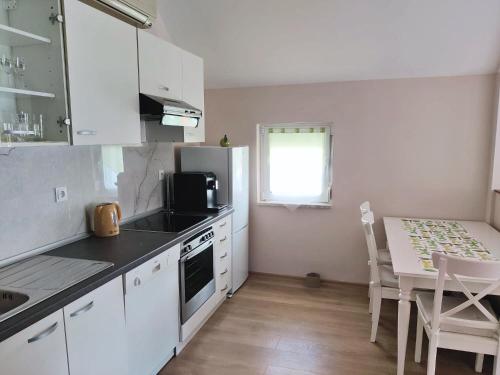 莫斯塔爾的住宿－Stella Apartments Mostar，厨房配有白色橱柜和带微波炉的桌子。