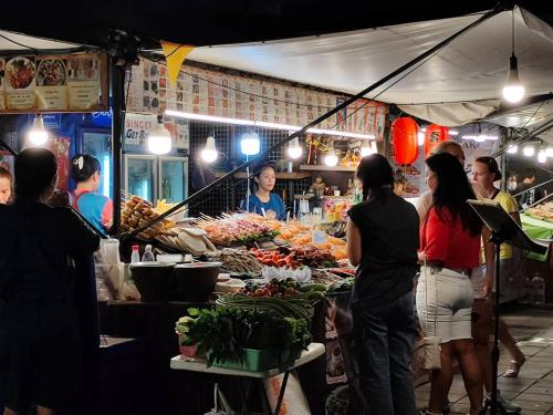a group of people standing around a market with food at Sea Hill Phatamnak Pattaya in Pattaya South
