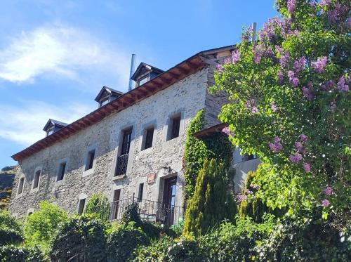 an old stone building with flowers in front of it at Hotel Rural LA CÁRCEL in Murias de Paredes