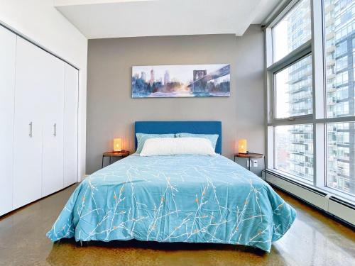 a bedroom with a blue bed and two windows at 2BR condo in downtown, w/ view+parking in Calgary