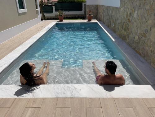 two people sitting in a swimming pool at Ocean Country Guest House Freiria in Freiria