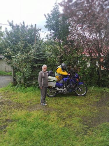 um homem mais velho parado em frente a uma moto em Ekolojik Güney Köy Pembe Köşk em Balçıklı