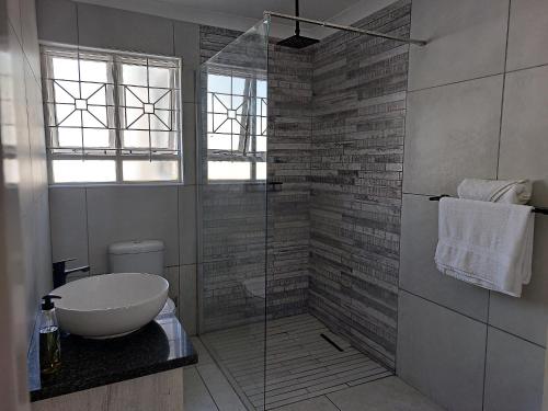 a bathroom with a sink and a glass shower at Grassland 4 (Townhouse) in Bloemfontein