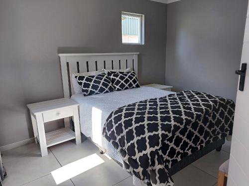 a bedroom with a bed with a black and white comforter at Grassland 4 (Townhouse) in Bloemfontein
