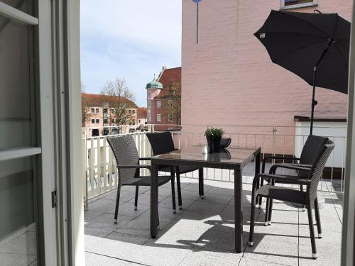a table and chairs on a balcony with an umbrella at Apartment 4-6 Personen I 80qm I Altstadt I Dachterasse I Parkplatz in Straubing