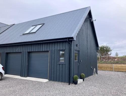 a black garage with two garage doors and a window at Berryfield Holiday Apartment in Inverness