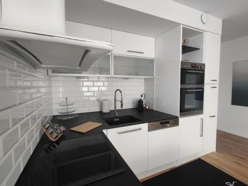 a kitchen with white cabinets and a black counter top at Bridge Apartment & Spa in Dziwnów