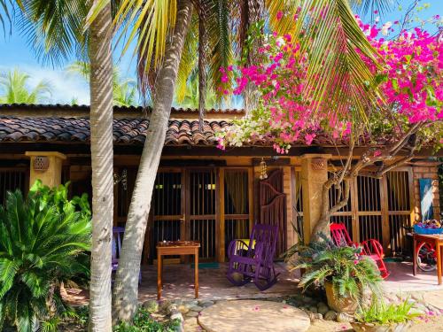 ein Haus mit Palmen, Stühlen und rosa Blumen in der Unterkunft Ocean Front Paradise in Petatlán