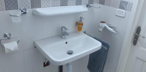 uma casa de banho branca com um lavatório branco e um espelho. em Chez Ayedi - central and familiar atmosphere next to beach em Hammam-Plage