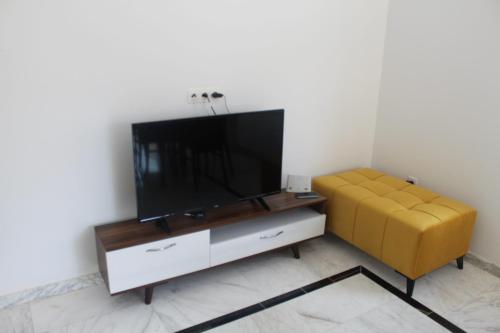 sala de estar con TV de pantalla plana y sofá amarillo en Relaxing Vacation Stay in Mahdia, en Rejiche
