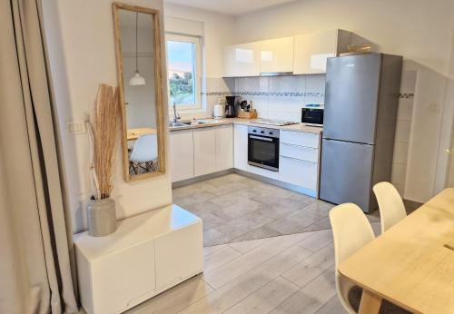 a kitchen with white cabinets and a table and a refrigerator at Apartments Nina in Rab