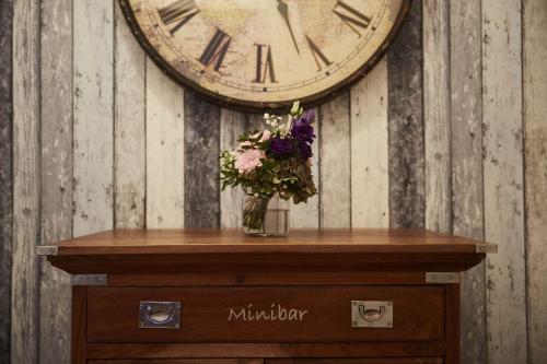 a vase of flowers on a table with a clock at Bernstein-Hotel Bootshaus in Büsum