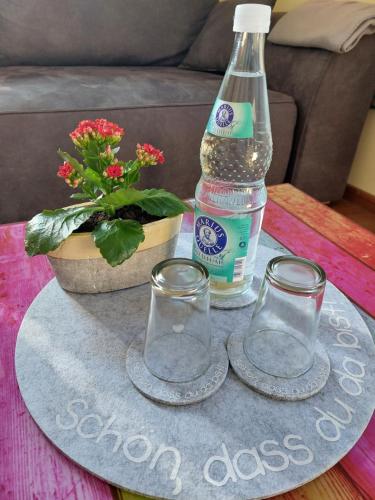 - une bouteille d'eau et deux verres sur une table dans l'établissement gemütliches Sandsteinhaus, à Buergstadt