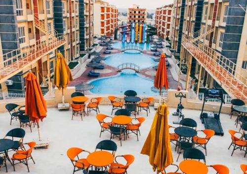 vistas a una piscina con mesas, sillas y sombrillas en شاليه فندقي للعائلات ريتال ڤيو حمام السباحه, en El Alamein