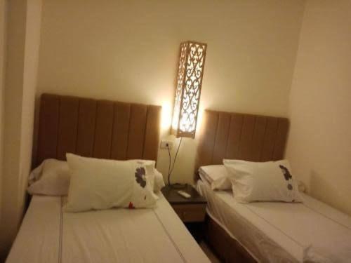 - une chambre avec 2 lits et une lumière sur le mur dans l'établissement شاليه فندقي للعائلات ريتال ڤيو حمام السباحه, à El Alamein