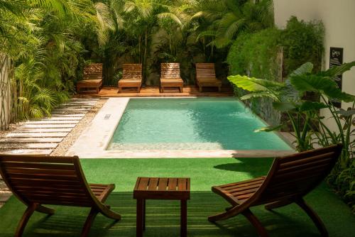 a swimming pool with two chairs and a table and two chairs at Hotel Muyu Tulum in Tulum