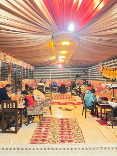 grupa ludzi siedzących przy stolikach w restauracji w obiekcie Wadi Rum Sunset Camp w mieście Wadi Rum