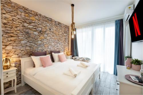 a white bed in a room with a stone wall at METROPOLE APARTMENTS ATENEUM RESIDENCE in Bucharest