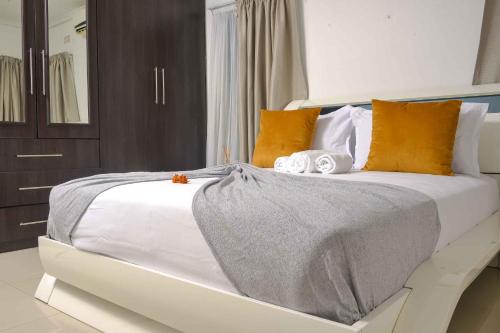 a bedroom with a large white bed with orange pillows at acaciaoptimumstay in Gaborone