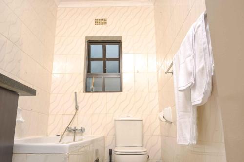 a white bathroom with a toilet and a sink at acaciaoptimumstay in Gaborone