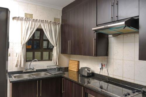 a kitchen with wooden cabinets and a sink and a window at acaciaoptimumstay in Gaborone