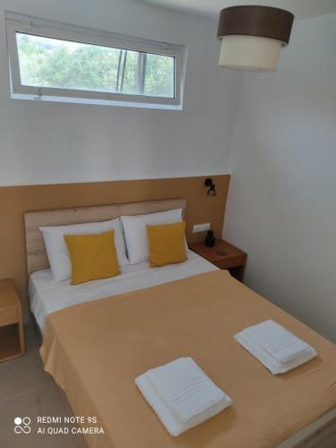 um quarto com uma cama com almofadas amarelas e uma janela em Studio Evridiki em Georgioupolis