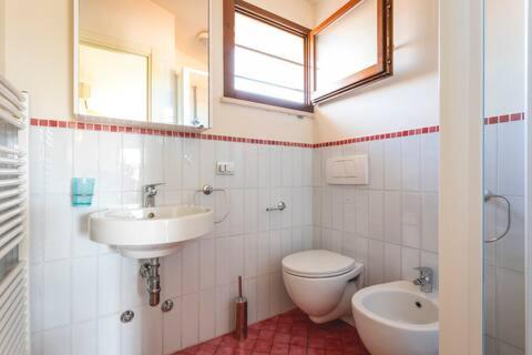 bagno con lavandino, servizi igienici e specchio di Appartamento Perla Marina a Milano Marittima