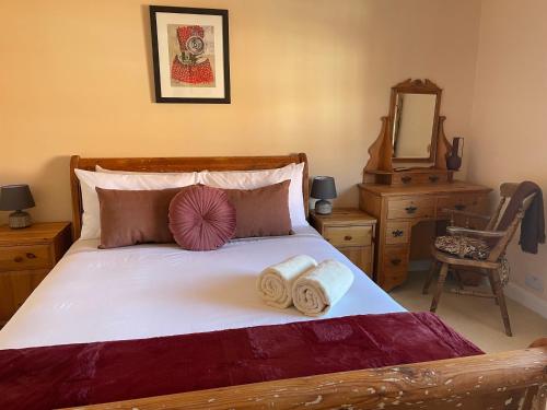 a bedroom with a bed with two towels and a mirror at Rasen Cottage in Lincolnshire