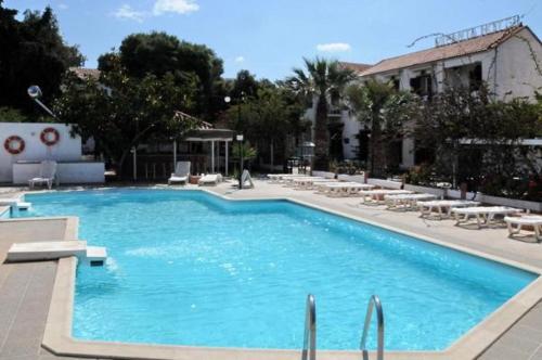 a large swimming pool with chairs and a building at Miranta Hotel - Apartments & Studios in Aegina Town