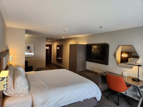 PerryにあるHoliday Inn Express & Suites Perry, an IHG Hotelのベッド、デスク、テレビが備わるホテルルームです。