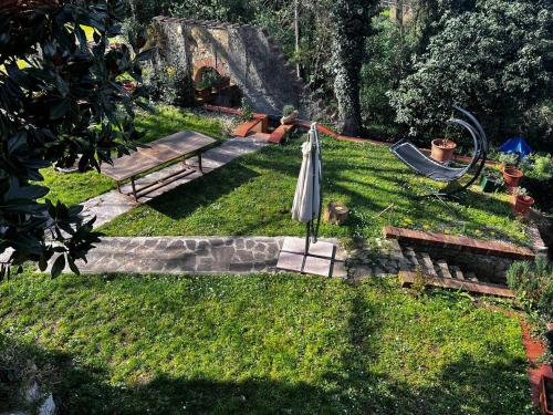 un parco con panchina e ombrellone nell'erba di Agriturismo Villa Paradiso - appartamenti con piscina a Fauglia
