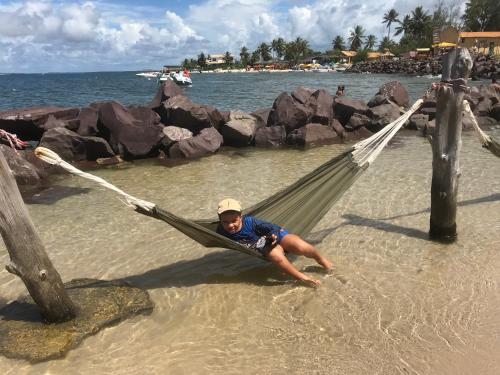 a man laying in a hammock on the beach at Villa das aguas -Praia do saco -Próximo as lagoas dos Tambaquis e Mangue Seco -térreo in Estância