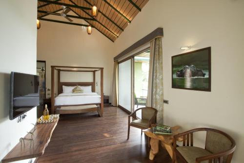 a bedroom with a bed and a table and a chair at Waterwoods Lodge Kabini in Begūr