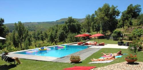 a group of people laying in the grass by a pool at Casa da Pedra - Turismo Rural in Bragado